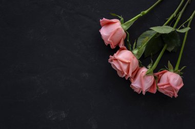 Yukarıdan gelen güzel bahar çiçekleri koyu arkaplanda. Güller, sarı çiçekler ve koylar