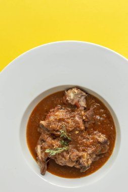 Geleneksel ev yapımı kuzu güveci ve aromatik bitkiler sarı arka planda düz yerde yatıyordu. Üst görünüm