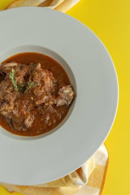 Geleneksel ev yapımı kuzu güveci ve aromatik bitkiler sarı arka planda düz yerde yatıyordu. Üst görünüm