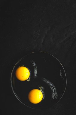 Yukardan koyu arkaplanda iki renk tavuk yumurtası. Düz katlı.