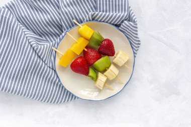 Muz, portakal, çilek, kivi ve mangolu sağlıklı meyve şişleri. Düz yatıyordu. Vejetaryen yemeği