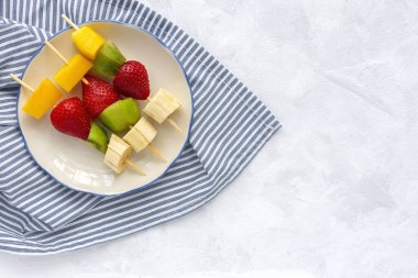 Muz, portakal, çilek, kivi ve mangolu sağlıklı meyve şişleri. Düz yatıyordu. Vejetaryen yemeği