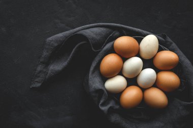 Yukardan koyu arkaplanda iki renk tavuk yumurtası. Düz katlı.