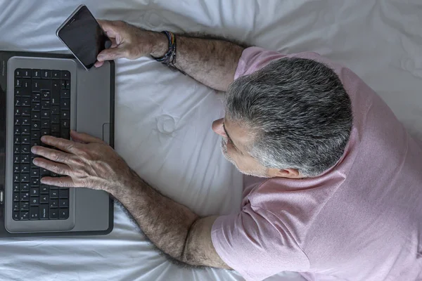 Hombre Maduro Con Barba Trabajando Cama Con Pijama Laptop Teléfono —  Fotos de Stock