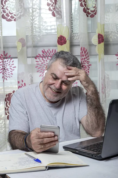 Starší Muž Plnovousem Pracuje Doma Pyžamem Notebookem Mobilním Telefonem Coronavirus — Stock fotografie