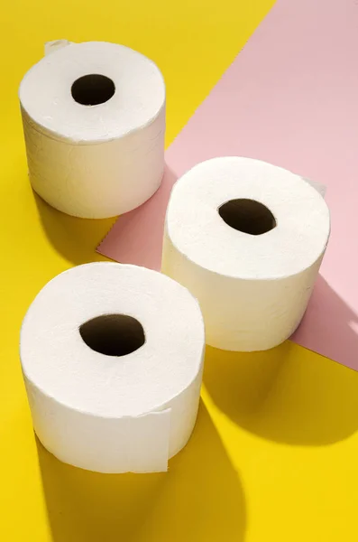 White toilet paper rolls on colored backgrounds with sunlight from above.Flat lay.Top view