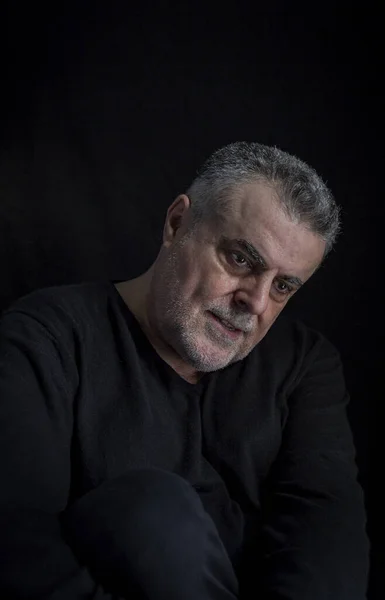 Dramatic portrait of mature man with classic hat and beard on dark background