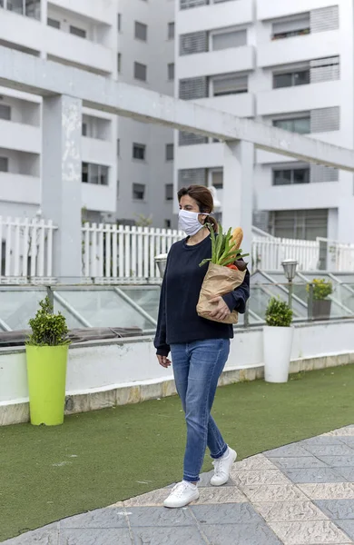 携带防腐面罩的成熟妇女在检疫返回家中购买基本产品时携带防腐面罩 — 图库照片