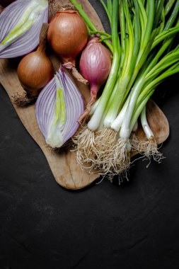 Koyu arkaplanda taze kırmızı ve beyaz soğan. Vejetaryen yemeği. Yiyecek.