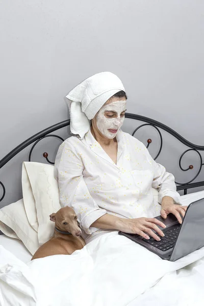 Mujer Madura Cuidando Cara Con Una Mascarilla Cama Con Perro —  Fotos de Stock