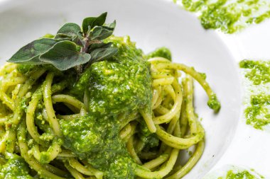 Ev yapımı pesto soslu spagetti ve beyaz arka planda keklik otu. İtalyan yemeği.