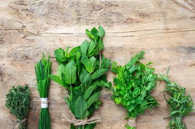 Eski ahşap arka planda yukarıdan taze aromatik bitkiler. Maydanoz, nane, kekik, fesleğen, Oregano, biberiye, soğan ve estragon.