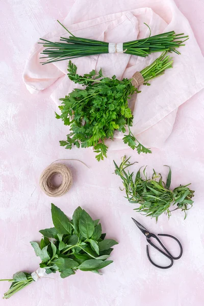 Assortment of fresh aromatic herbs from above on pink background. Parsley, Mint, Thyme, Basil, Oregano, Rosemary, Chives and estragon.Flat lay.Top view
