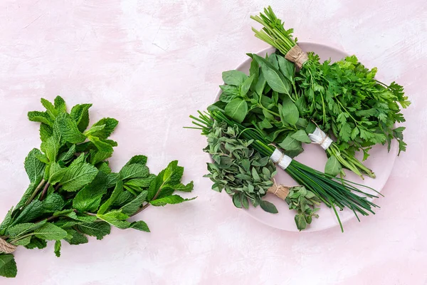 Assortment of fresh aromatic herbs from above on pink background. Parsley, Mint, Thyme, Basil, Oregano, Rosemary, Chives and estragon.Flat lay.Top view
