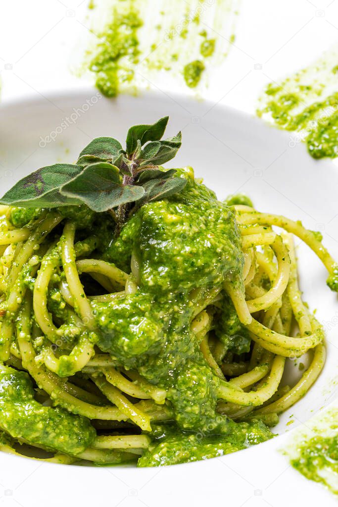 Spaghetti with homemade pesto sauce and oregano on white background.Italian food