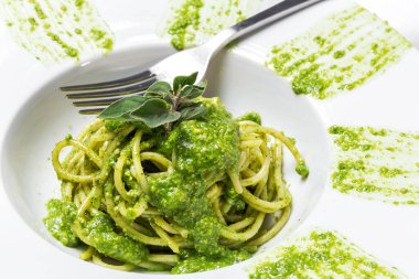 Ev yapımı pesto soslu spagetti ve beyaz arka planda keklik otu. İtalyan yemeği.