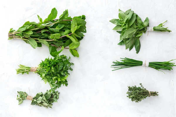 Assortment of fresh aromatic herbs from above on white background. Parsley, Mint, Thyme, Basil, Oregano, Rosemary, Chives and tarragon.Flat lay.Top view