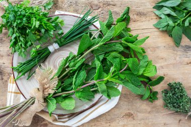 Eski ahşap arka planda yukarıdan taze aromatik bitkiler. Maydanoz, nane, kekik, fesleğen, Oregano, biberiye, soğan ve estragon.