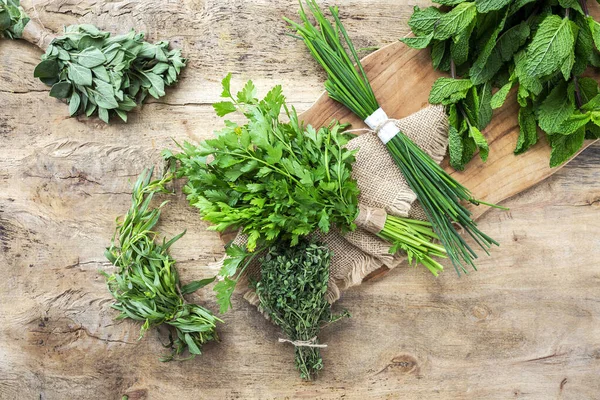 Eski ahşap arka planda yukarıdan taze aromatik bitkiler. Maydanoz, nane, kekik, fesleğen, Oregano, biberiye, soğan ve estragon.