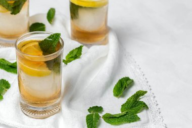 Beyaz masada buzlu, naneli ve limonlu çay bardaklarını tazeliyorum.