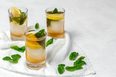 Beyaz masada buzlu, naneli ve limonlu çay bardaklarını tazeliyorum.