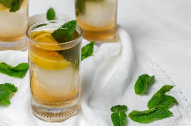 Beyaz masada buzlu, naneli ve limonlu çay bardaklarını tazeliyorum.