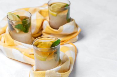 Beyaz masada buzlu, naneli ve limonlu çay bardaklarını tazeliyorum.