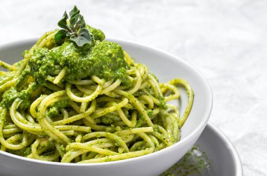 Ev yapımı pesto soslu spagetti ve gri arka planda kekik otu. İtalyan yemeği.