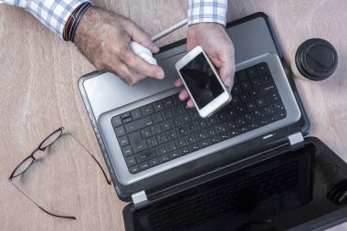 COVID-19. Çalışma masasında hidrojeli, dizüstü bilgisayarı, cep telefonu ve gözlüklü cep telefonu dezenfeksiyonu. Koronavirüs salgını