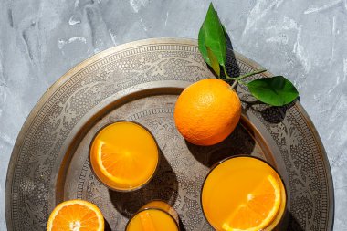 Yukardan ev yapımı portakal suyu. Gri arkaplanda güneş ışığı. Düz açılı.