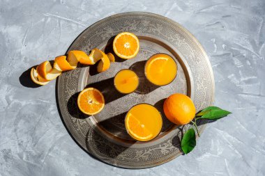 Yukardan ev yapımı portakal suyu. Gri arkaplanda güneş ışığı. Düz açılı.