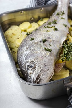 Patates, kekik ve limonla kızartılmaya hazır taze çiğ Corvina balığı. Deniz ürünleri. Corvin. Ev yapımı.