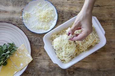 Geleneksel ev yapımı İtalyan deniz ürünleri ve peynirli lazanyayı eski ahşap arka planda hazırlayan eller. Yemek tarifi. İtalyan yemeği.