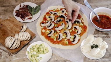 Şefin elleri ev yapımı pizza hamuru yapıyor ve domates, mantar, jambon, mozzarella ve parmesan peyniri ile hazırlanıyor. İtalyan yemeği.