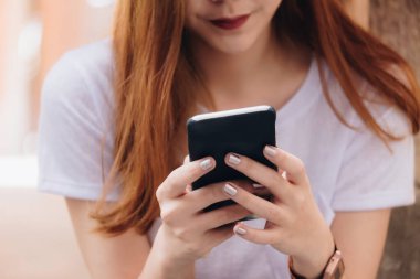 Asyalı iş kadını kafeteryada otururken akıllı telefon kullanıyor. Cep telefonu kullanan gençler kavramı.