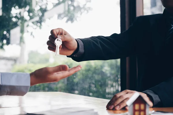 real estate agent holding house key to his client after signing contract,concept for real estate, moving home or renting propert