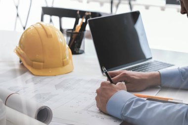 Ofiste planlarla çalışan mimar veya mühendis, mimari planlama için işyerinde mühendis teftişi, bir inşaat projesi çizimi, seçici odaklanma, iş kurma konsepti