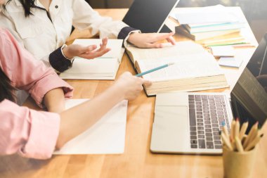 Masada otururken dizüstü bilgisayar kullanarak lise ya da üniversite. Grup öğrencileri kütüphanede kitap okuyup ders çalışıyor. Öğrenciler arkadaşlara yetişip özel ders öğrenmelerine yardımcı olur. eğitim kavramı