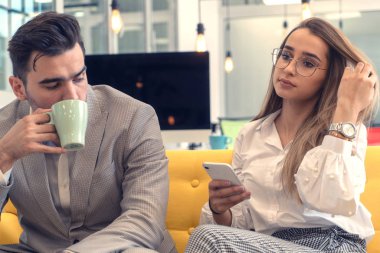 Takım elbiseli bir adam ve güzel bir kadın telefonda oturup çalışıyor.