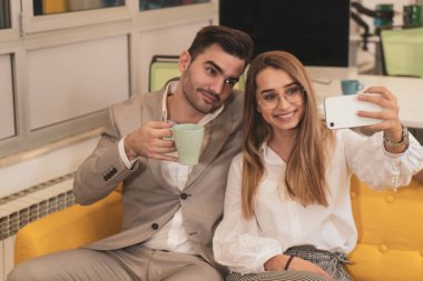 Takım elbiseli bir adam ve güzel bir kadın telefonda oturup çalışıyor.