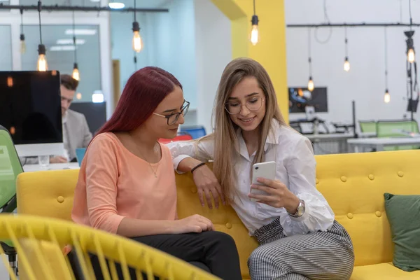Dos mujeres sentadas y trabajando en el teléfono — Foto de Stock