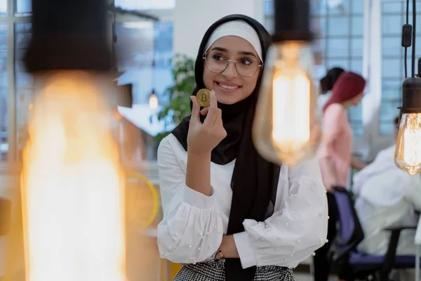 Young arabian muslim woman in hijab black clothes hold in hand holding bitcoin. Cryptocurrency exchange — 스톡 사진