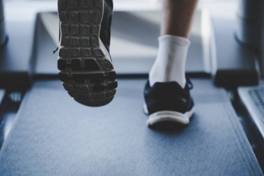 Sporcu spor salonunda koşu bandında egzersiz yapıyor.
