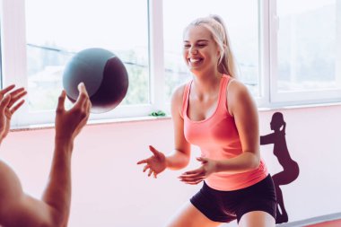 Modern spor salonunda topla egzersiz yapan kaslı bir çift.