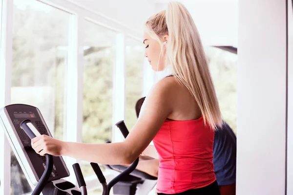 Fit woman on exercise bike wiping sweat with towel at the gym — Stock Photo, Image
