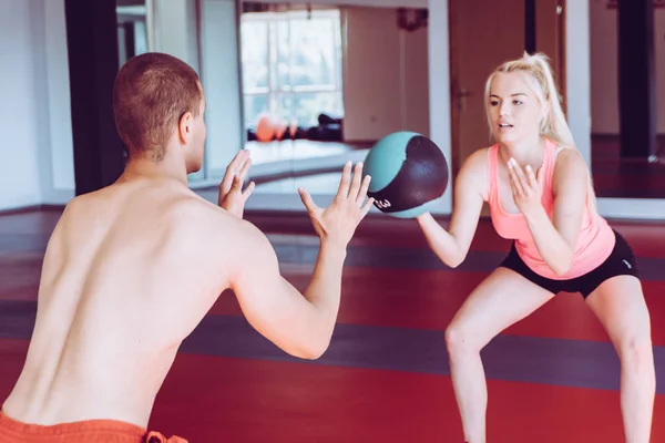 Muscular couple doing exercises with ball in modern gym — Stock Photo, Image