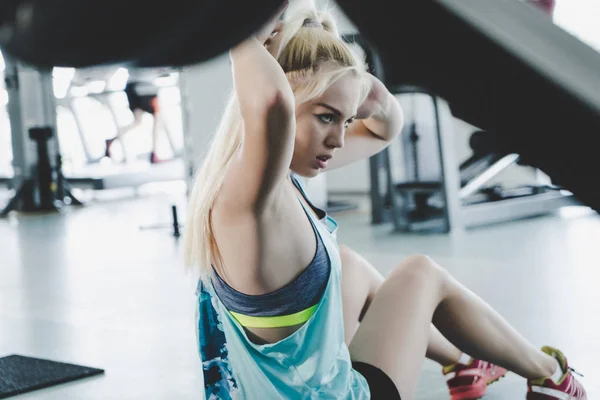Retrato de una mujer fitness haciendo ejercicios abdominales en el gimnasio —  Fotos de Stock