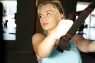 Sportif kadın spor salonunda trx egzersizleri yapıyor