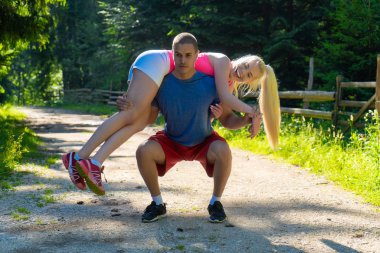 Genç spor çifti ormanda egzersiz yapıyor.