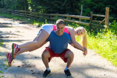 Genç spor çifti ormanda egzersiz yapıyor.